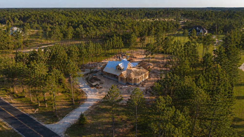 Aerial view of a rural custom home build in progress on a wooded Walker County lot