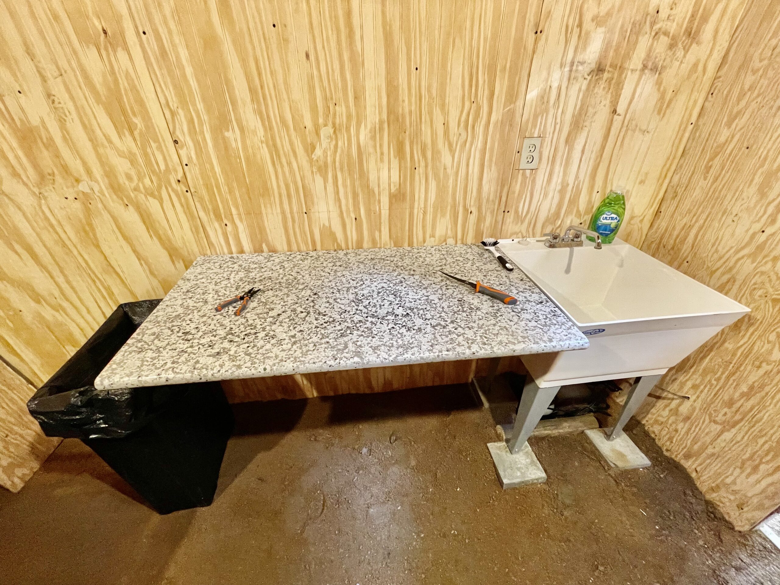 Fish cleaning station with stone counter and slop sink in storage shed