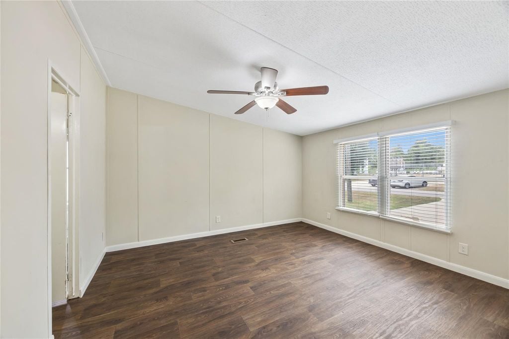 Spacious primary bedroom with ceiling fan and natural light